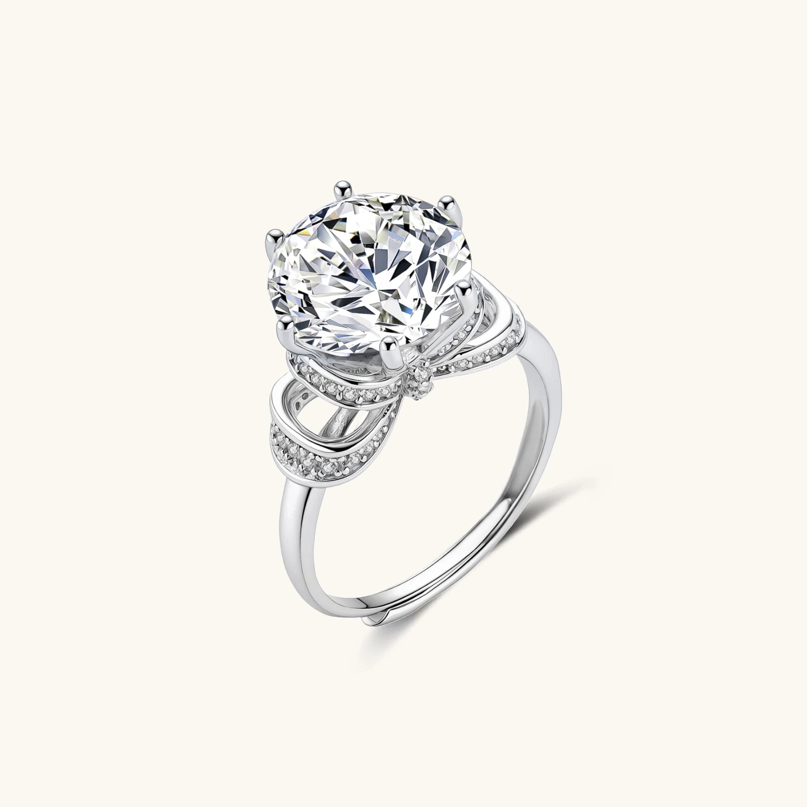 Sterling silver ring with 5ct round moissanite center stone and intricate bow design with pavé accents on white background.