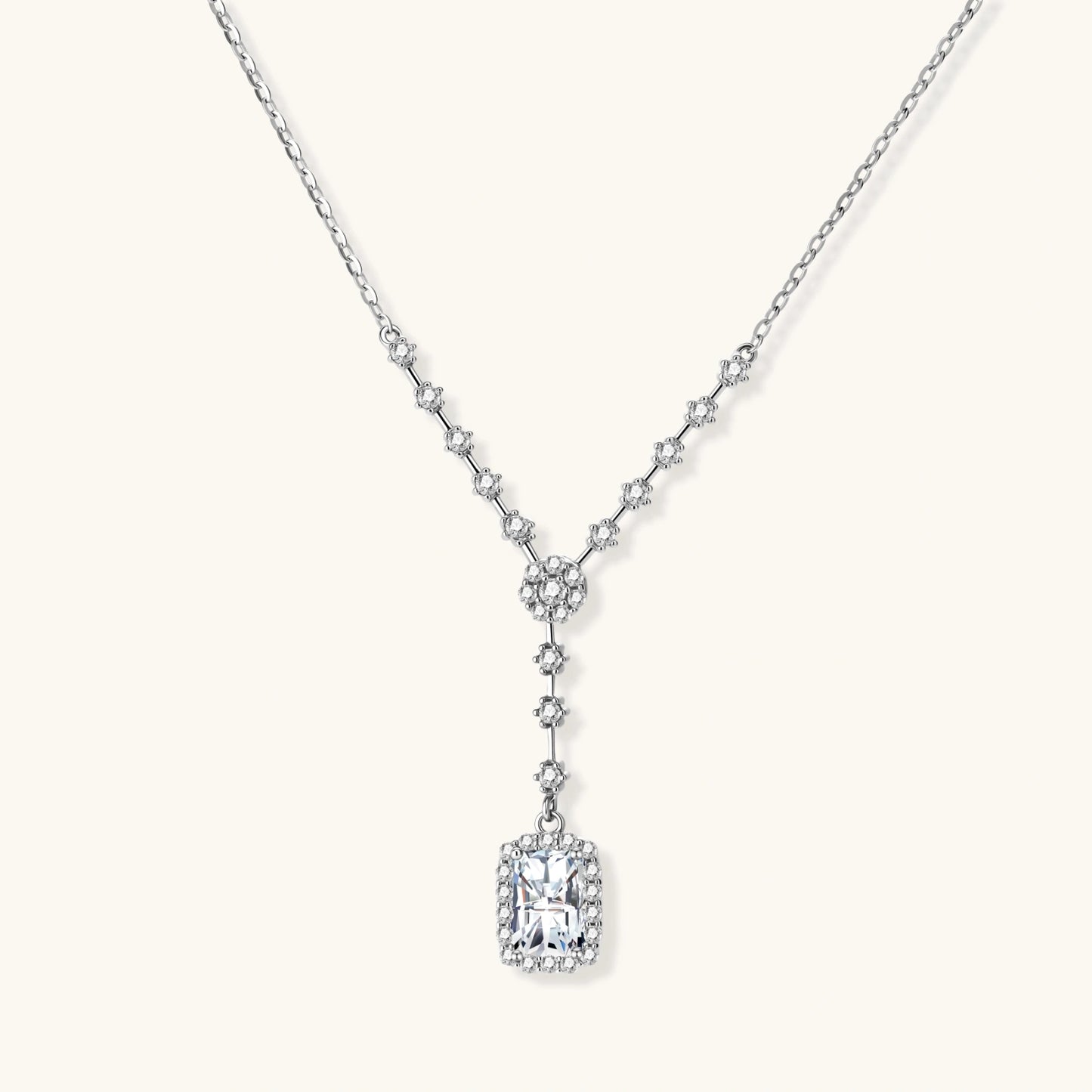 Sterling silver Y-necklace with rectangular moissanite pendant in halo setting and cascading accent stones on white background.
