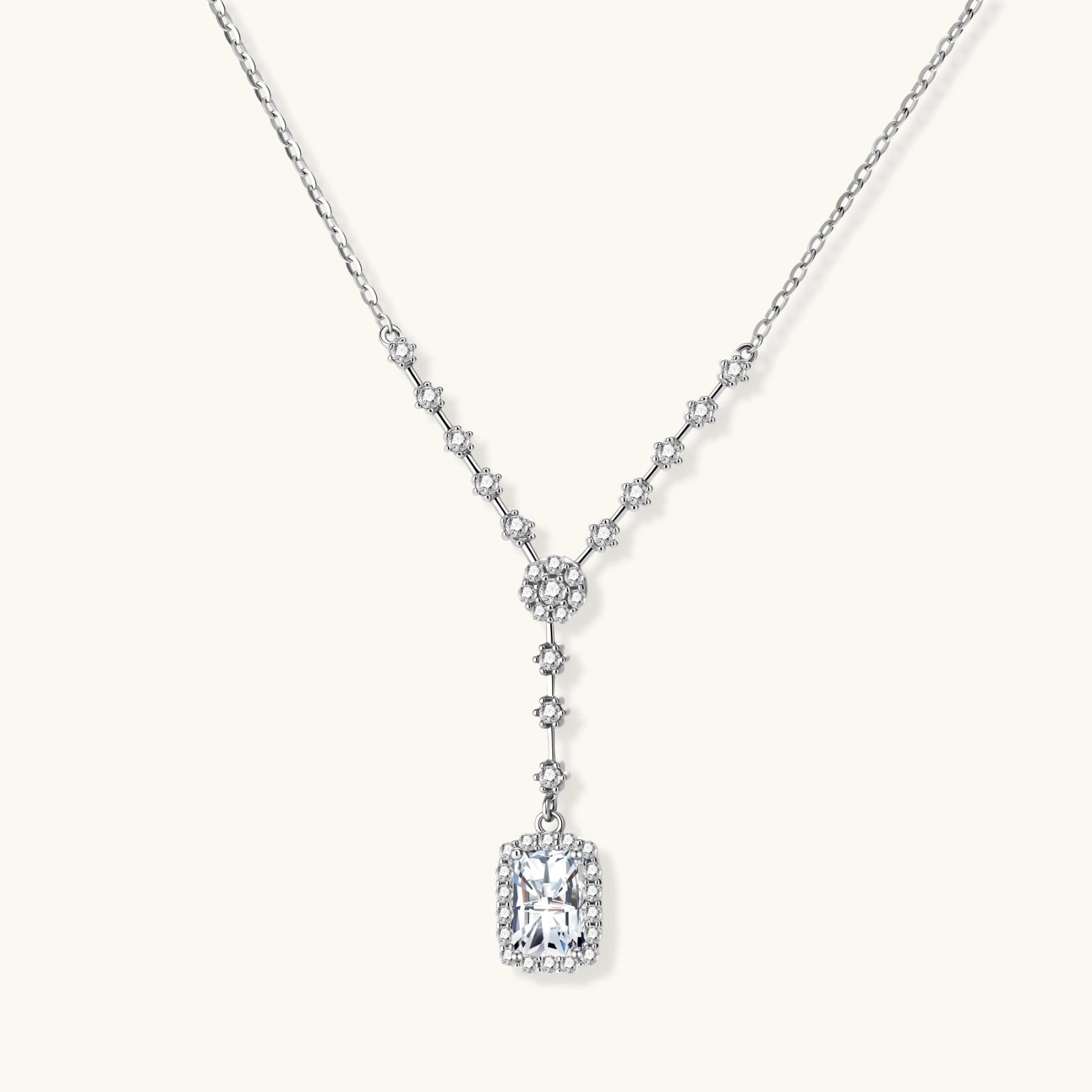 Sterling silver Y-necklace with rectangular moissanite pendant in halo setting and cascading accent stones on white background.