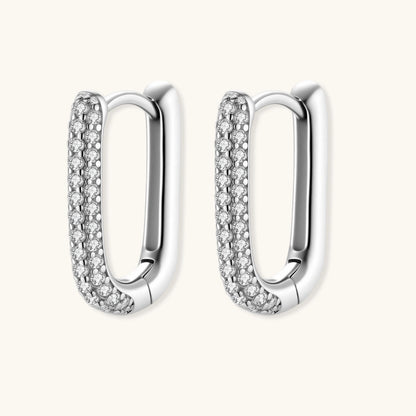 Close-up of platinum-plated sterling silver huggie hoops with pavé crystal setting on white background.