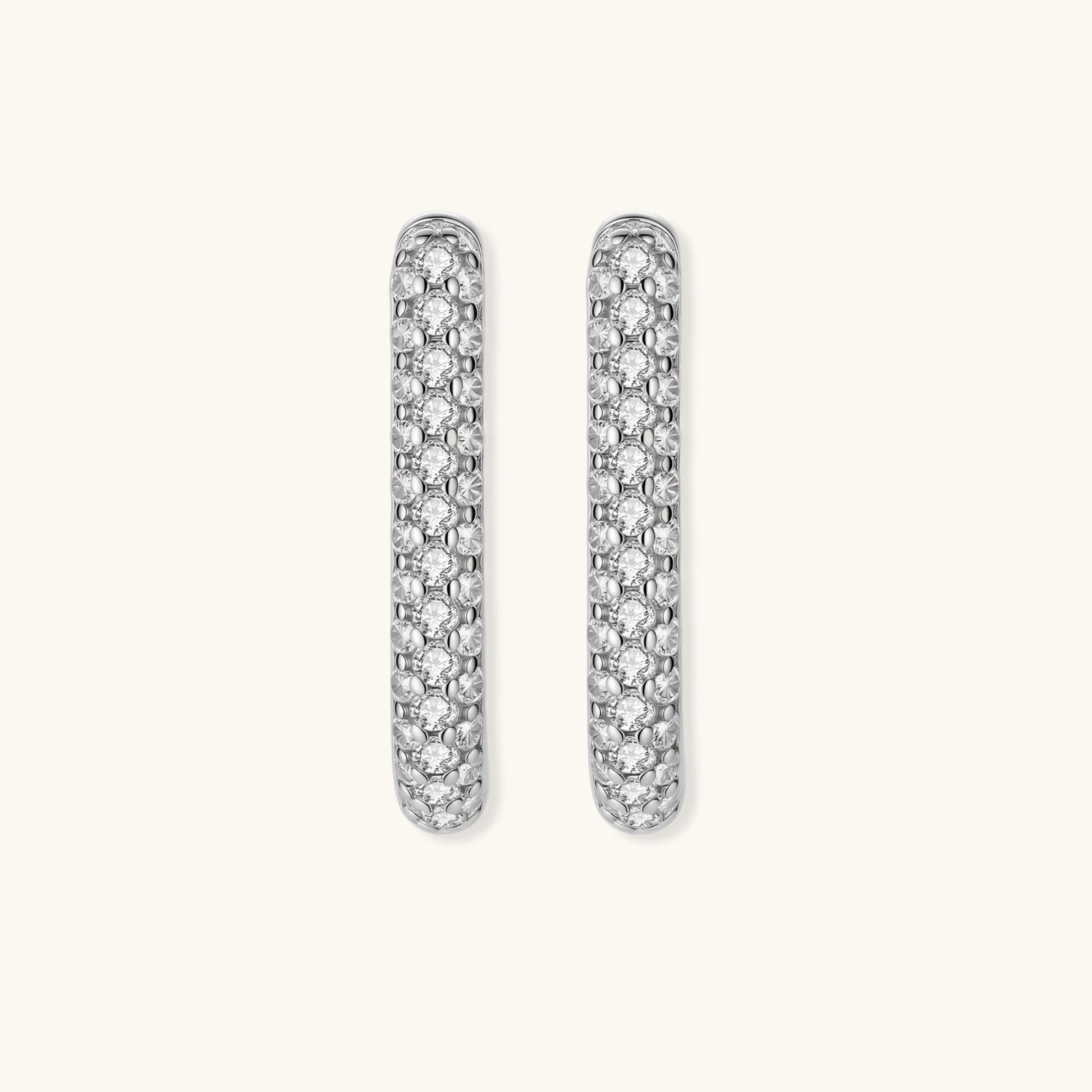 Close-up of platinum-plated sterling silver huggie hoops with pavé crystal setting on white background.