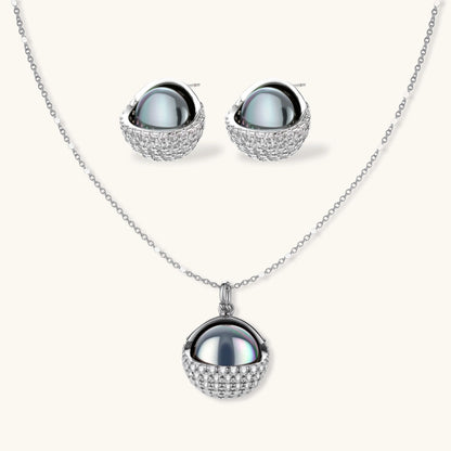 White gold plated spherical jewelry set with zirconia crystal pavé and dark lustrous centers on neutral background.