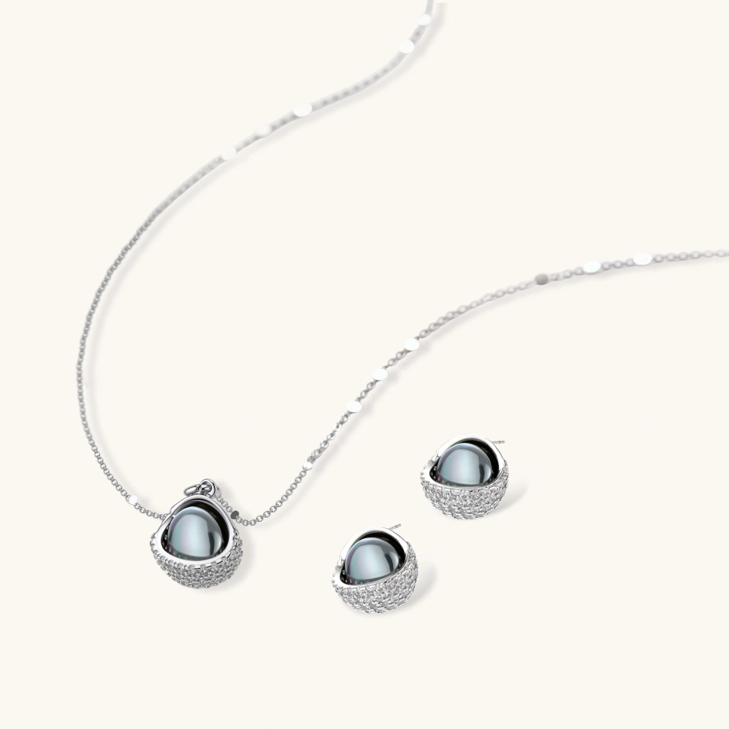 White gold plated spherical jewelry set with zirconia crystal pavé and dark lustrous centers on neutral background.