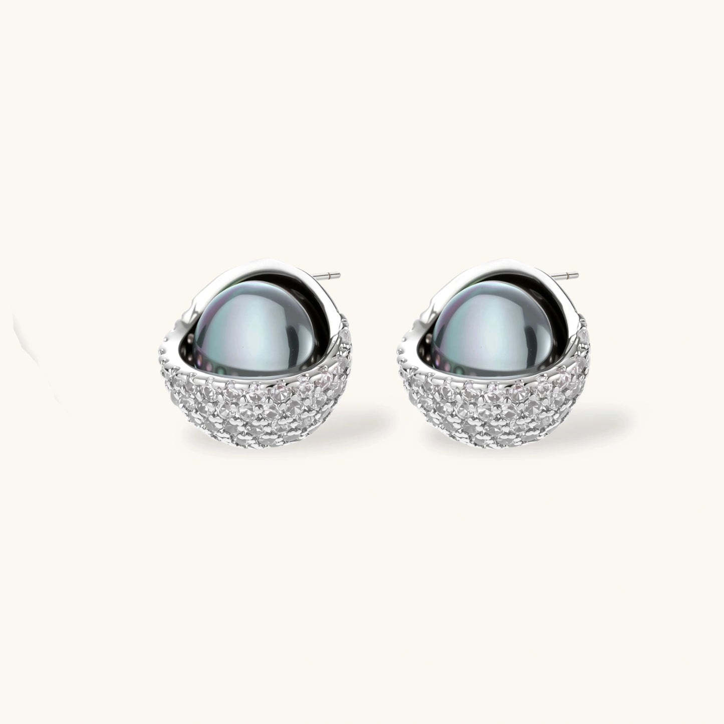 White gold plated spherical jewelry set with zirconia crystal pavé and dark lustrous centers on neutral background.