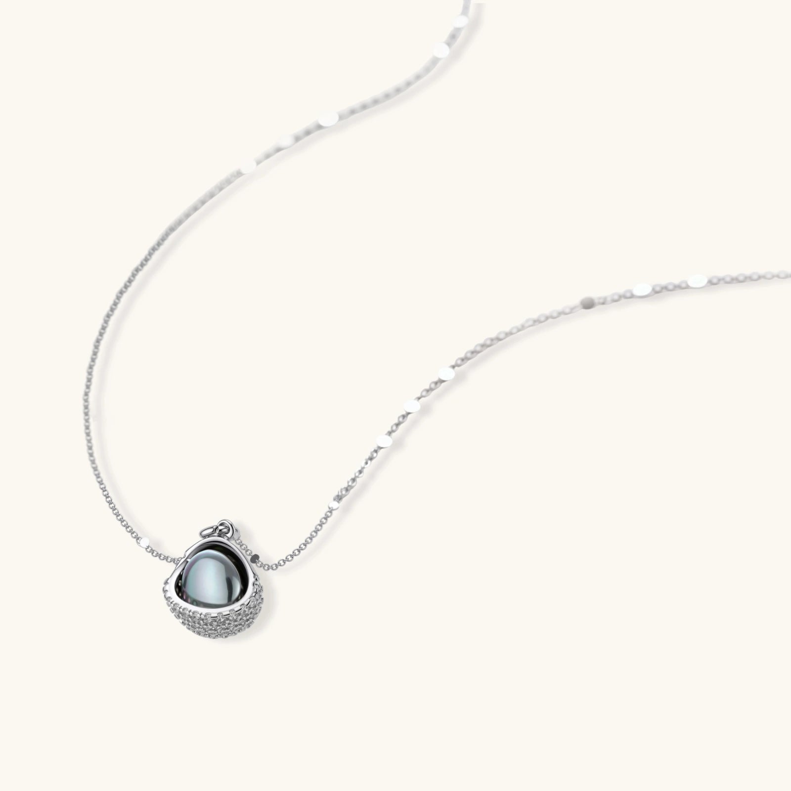 White gold plated spherical jewelry set with zirconia crystal pavé and dark lustrous centers on neutral background.