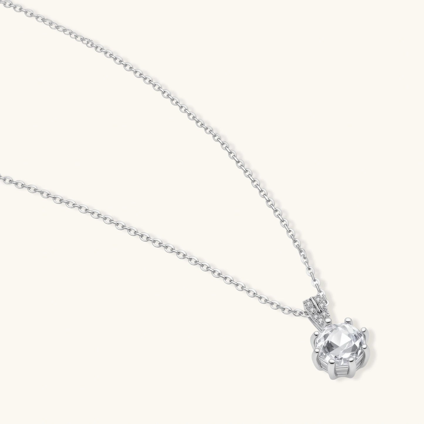 Platinum-plated sterling silver necklace with round clear crystal pendant and decorative bail on neutral background.