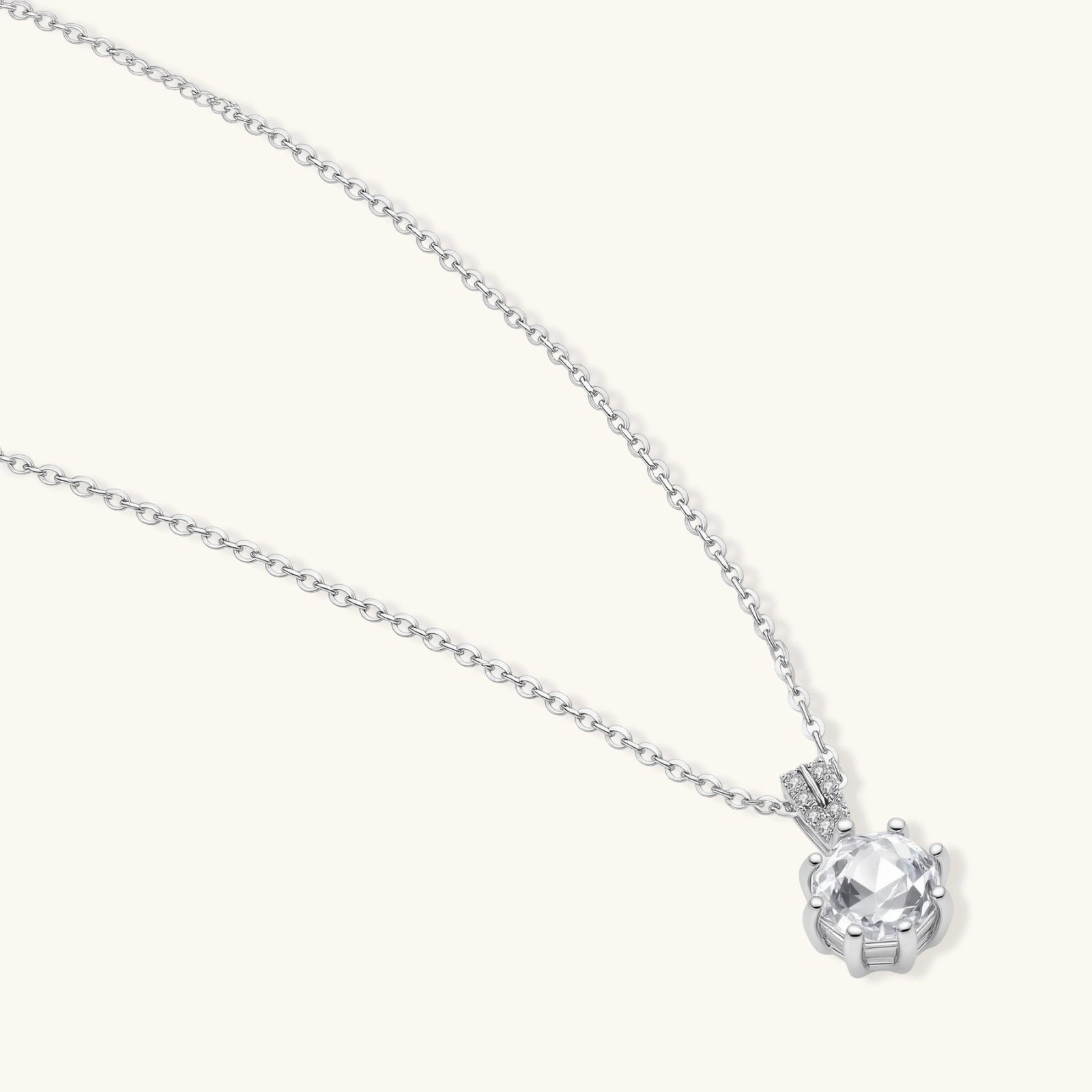 Platinum-plated sterling silver necklace with round clear crystal pendant and decorative bail on neutral background.