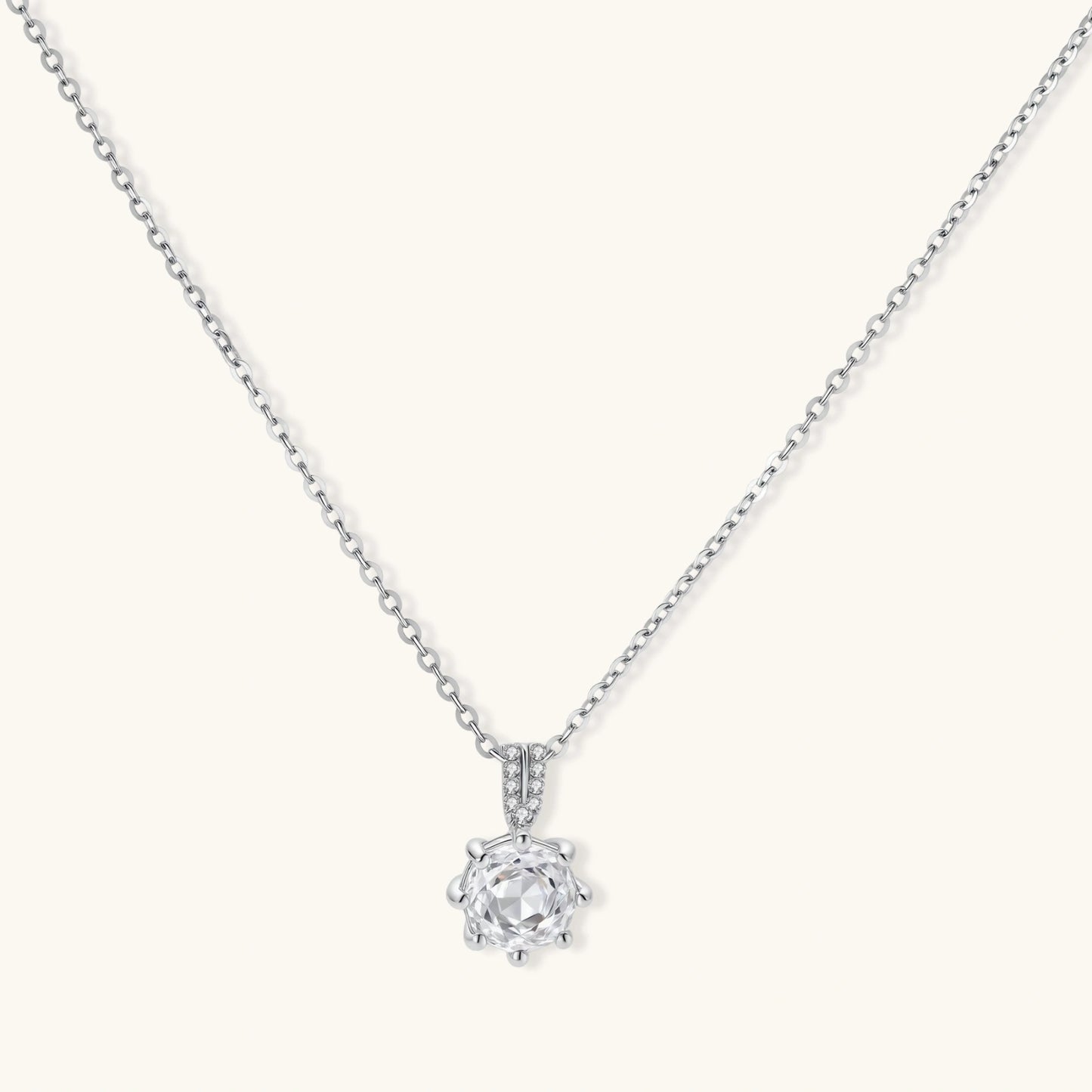 Platinum-plated sterling silver necklace with round clear crystal pendant and decorative bail on neutral background.