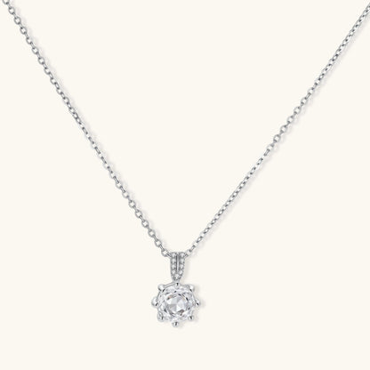 Platinum-plated sterling silver necklace with round clear crystal pendant and decorative bail on neutral background.