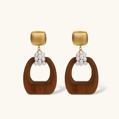 Gold-plated stud earrings with pearl clusters and organic brown wooden hoops on cream background