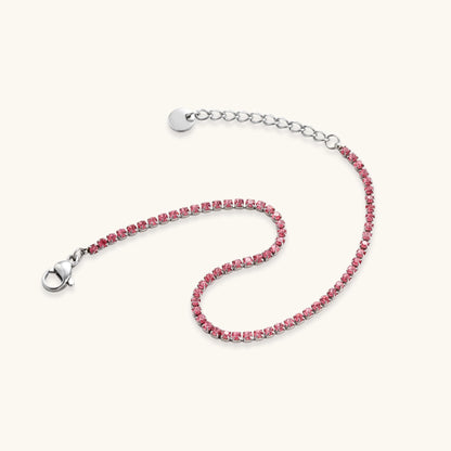 Pink zircon tennis bracelet with silver-tone stainless steel setting and lobster clasp extender chain, flat lay.
